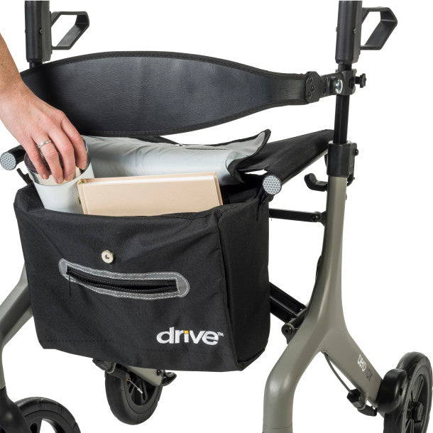 Black bag attached to a walker with a person's hand reaching into it, containing books and a pillow.
