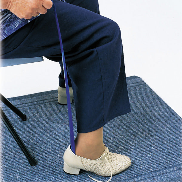 Person sitting on a chair with a blue resistance band around their leg on a blue textured floor.