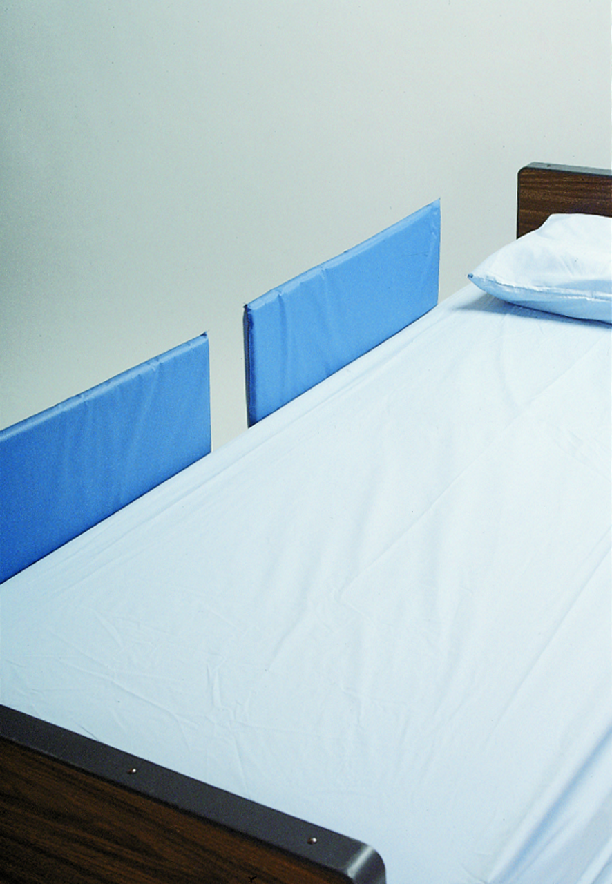 Bed with blue side rails against a plain wall