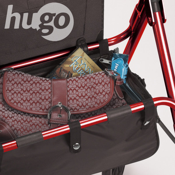 Red and black stroller with a patterned bag and books inside, branded 'hugo'.
