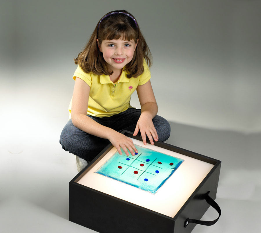 Child interacting with a light box featuring colorful shapes