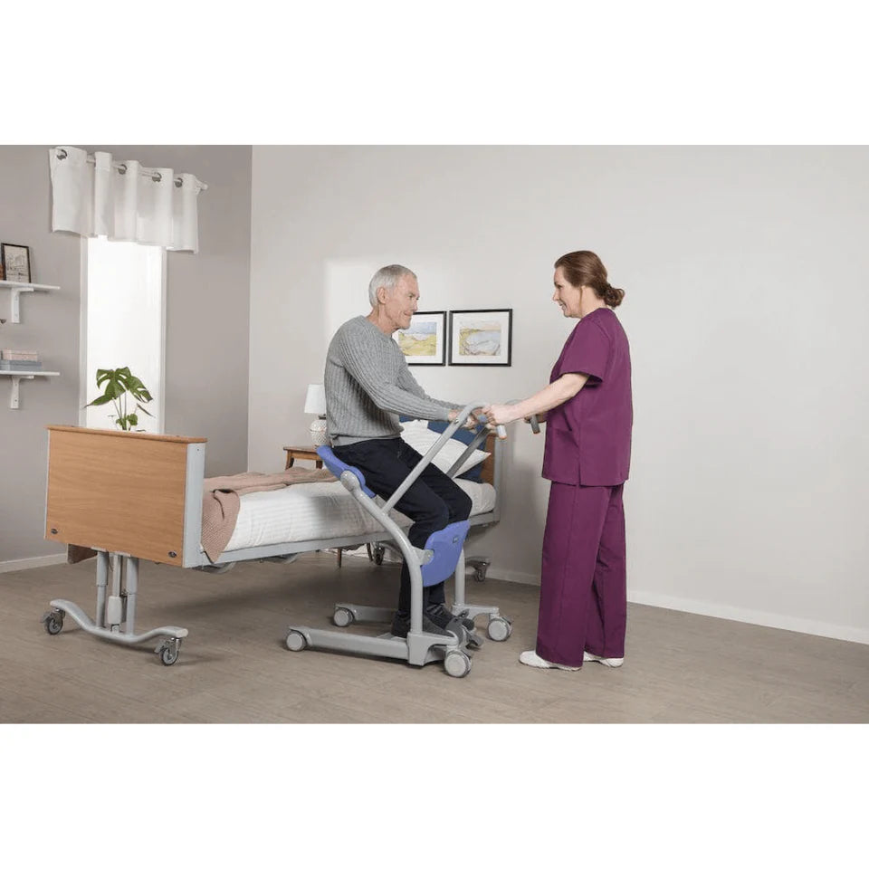 Person using a hospital bed with a healthcare professional assisting them.