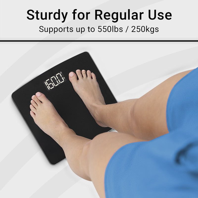 Person stepping on a digital bathroom scale with text indicating weight capacity.