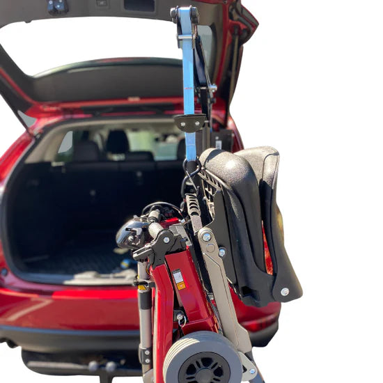 Red mobility scooter with folded chair attached to a car's open trunk.