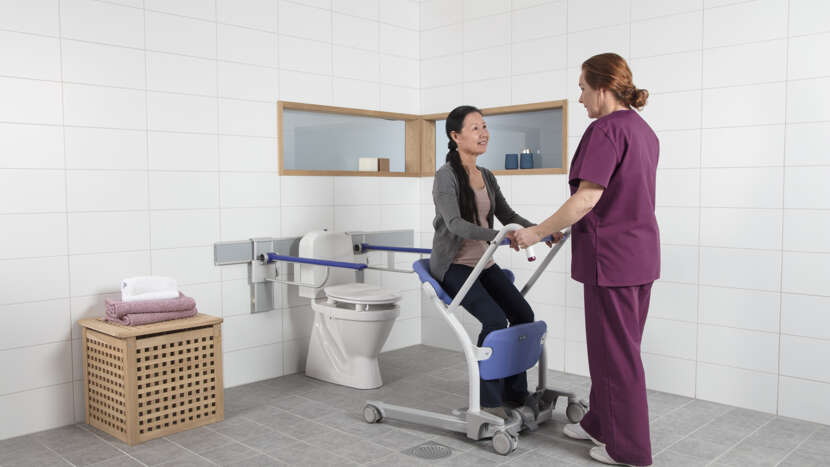 Person using a wheelchair with assistance in a bathroom setting
