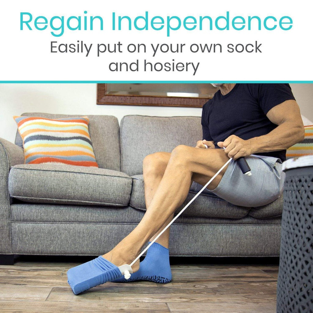 Person using a sock aid to put on socks in a living room.