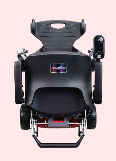 Back view of a black power wheelchair with 'Freelider' branding on a pink background