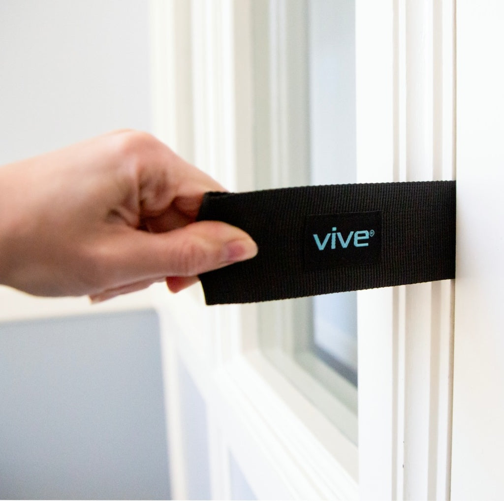 Hand holding a black strap with 'Vive' logo against a window background