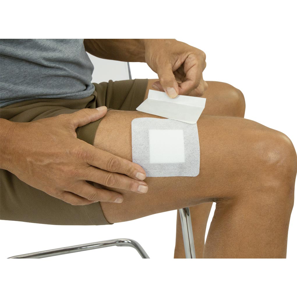 Person applying a bandage to their knee on a white background