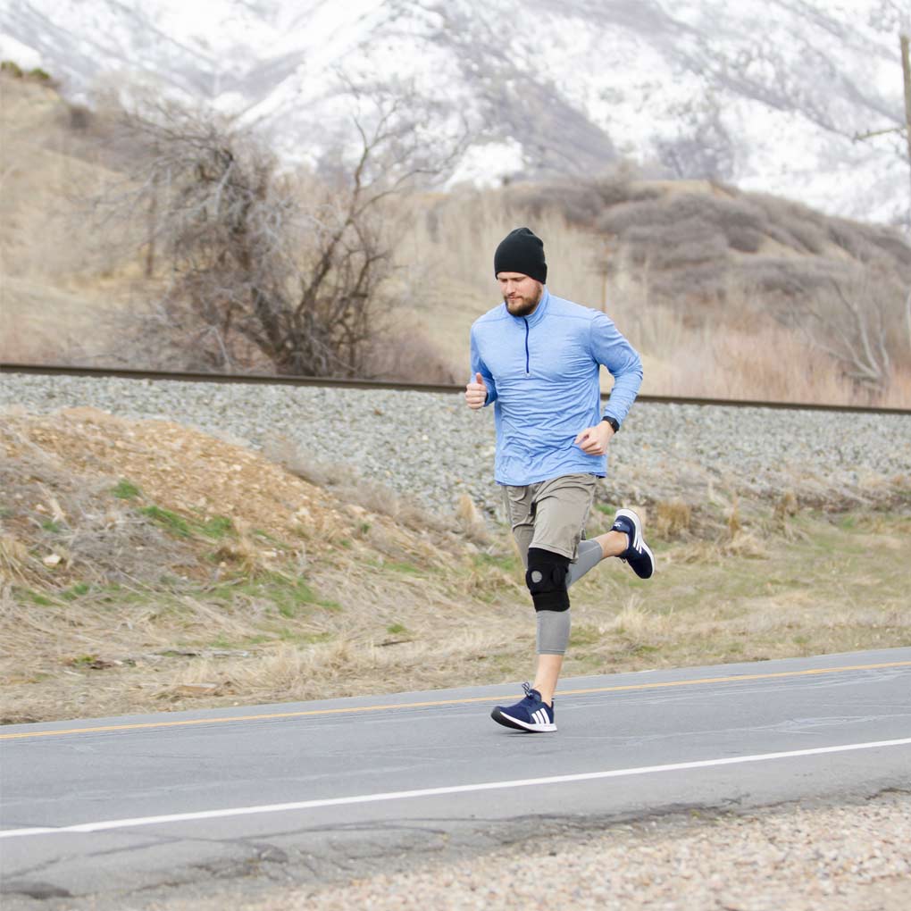 Man running on a road with mountains in the background