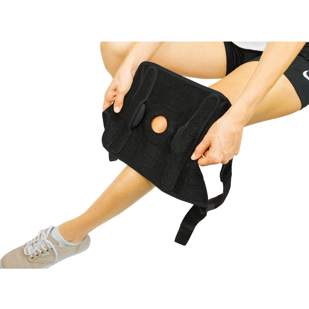 Person using a black knee brace on a white background