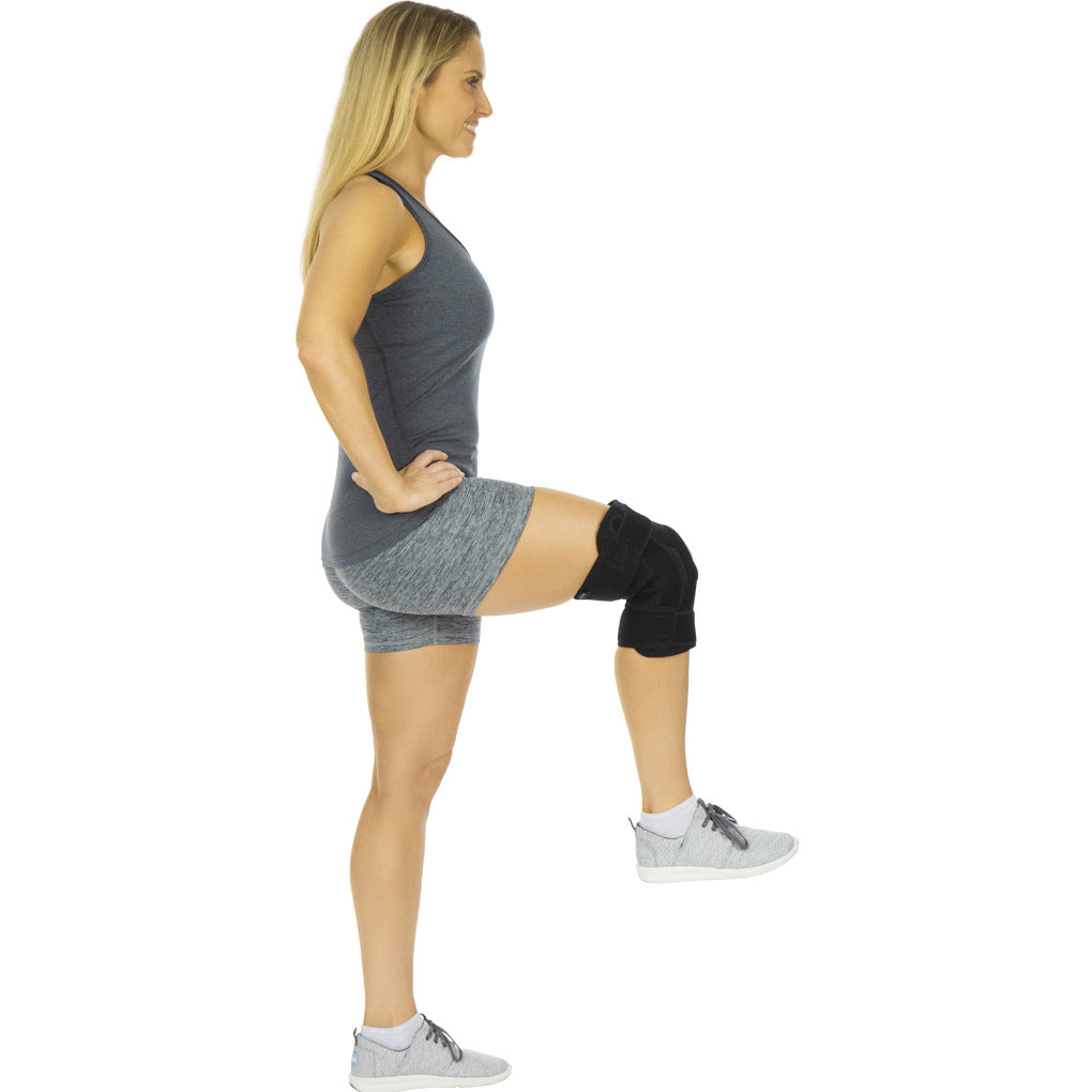 Woman wearing a gray dress and black knee brace on a white background
