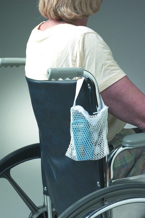 Person in a wheelchair with a white mesh bag attached to the backrest.