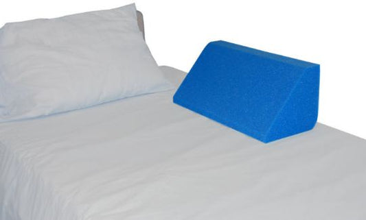 Blue wedge pillow on a bed with white pillows