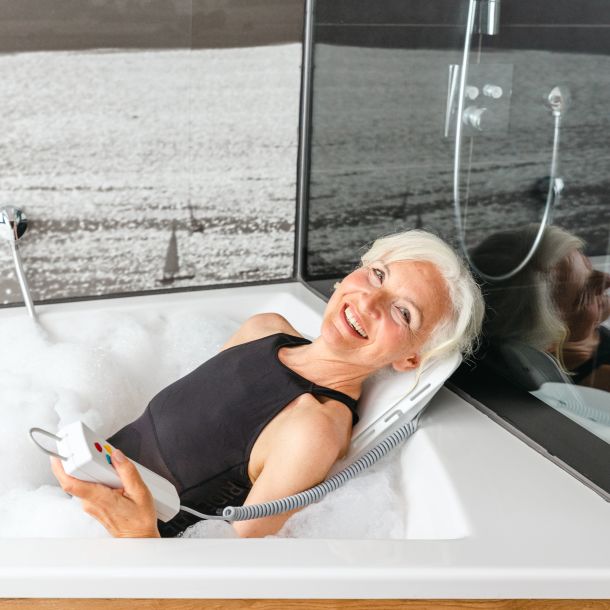 Woman lying in a hydrotherapy tub with water flowing over her.