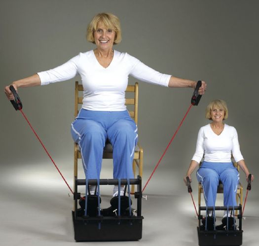 Woman using resistance bands with a chair on a gray background
