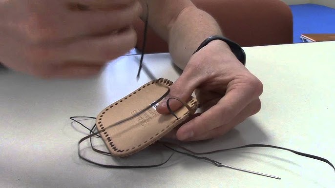 Person working on a leather item with strings on a table