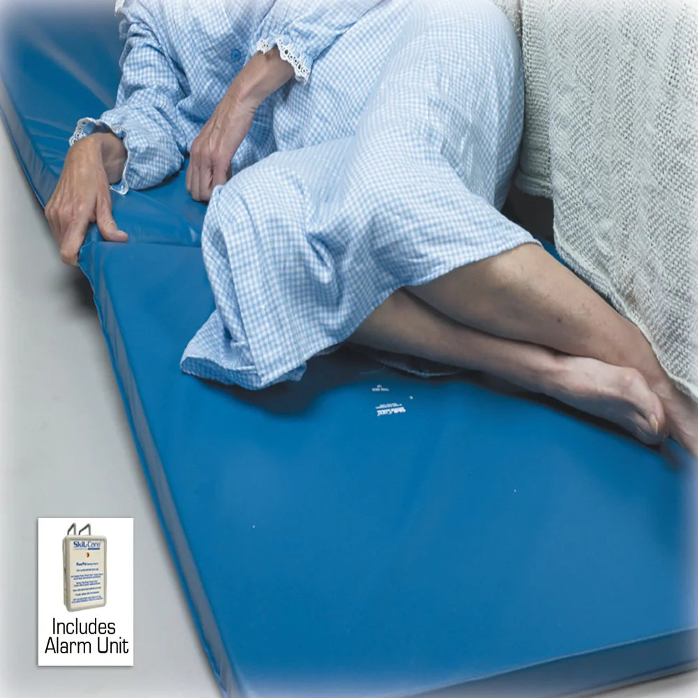 Person lying on a blue mattress with a label indicating an alarm unit included.