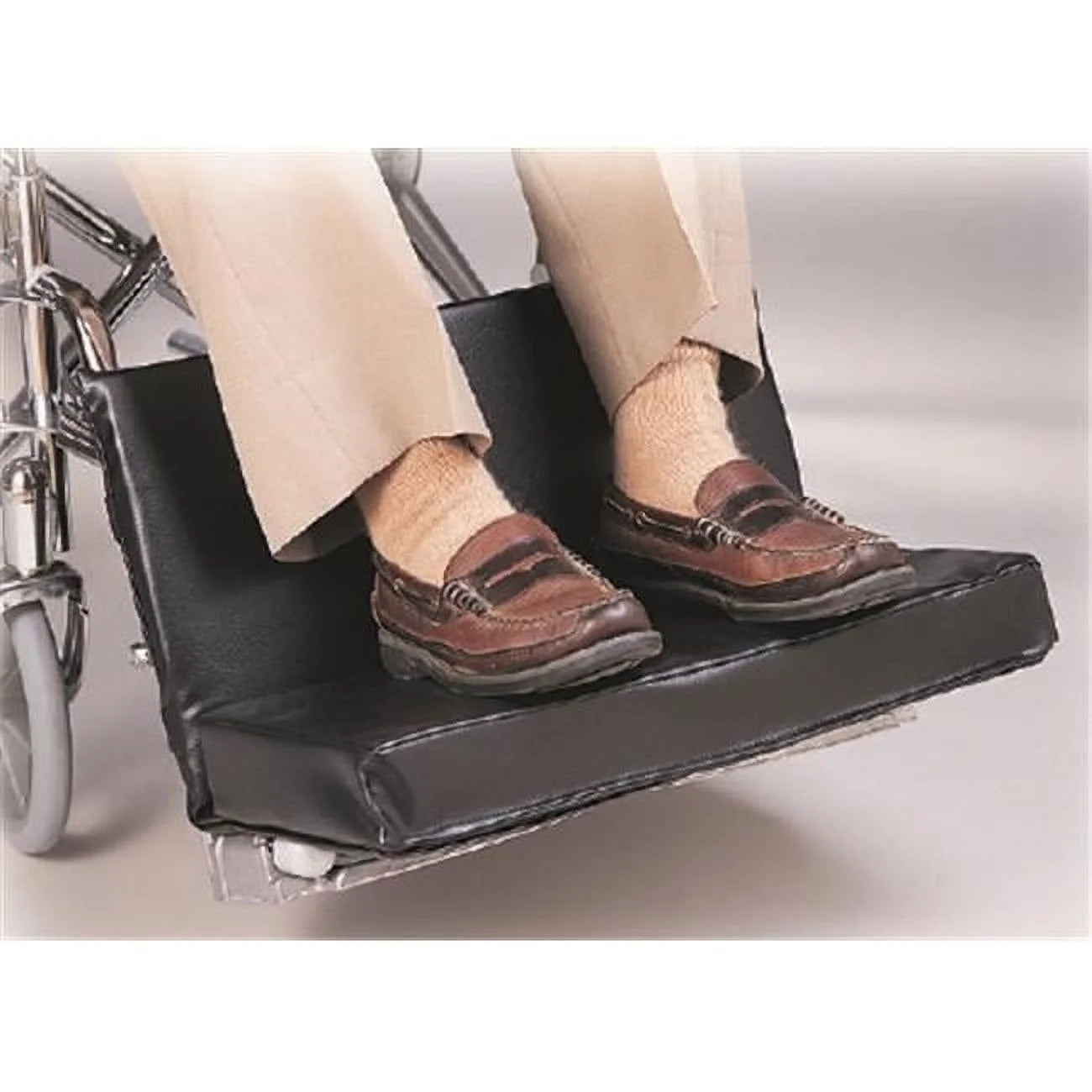 Wheelchair with a footrest extension showing a person's feet wearing brown shoes.