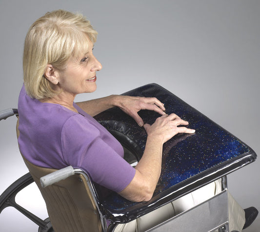 Woman using a wheelchair with a black tray attached to the backrest.
