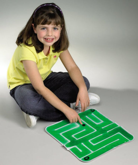 Child playing with a maze toy on a gray floor