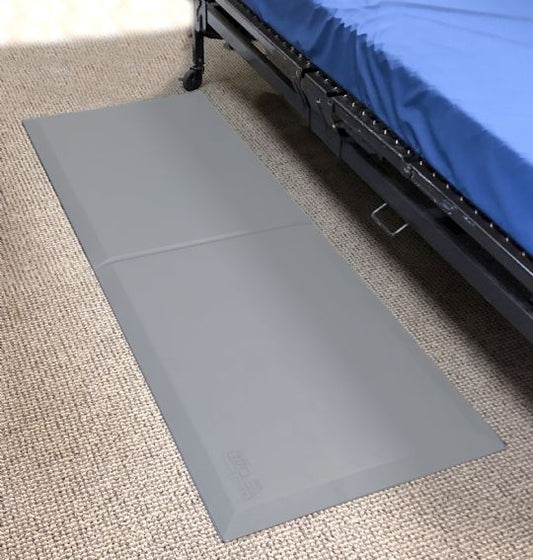 Gray mat on a carpeted floor next to a bed with blue bedding.