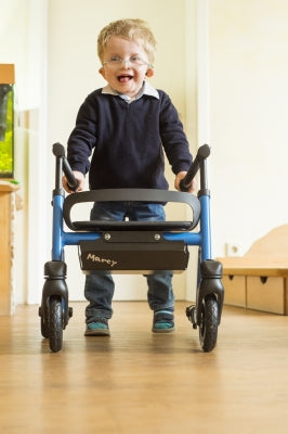 Child using a walker indoors with a neutral background