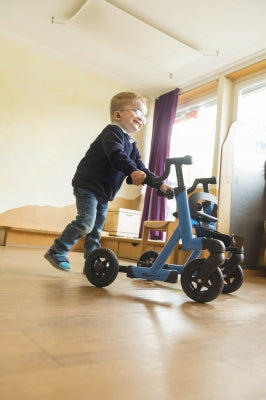 Child playing with a blue scooter indoors