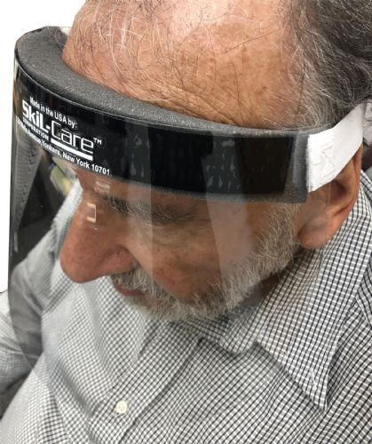 Person wearing a Skil-Care face shield with a checkered shirt.