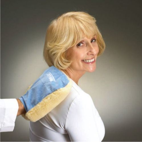 Woman wearing a blue and yellow heating pad on her shoulder against a gray background