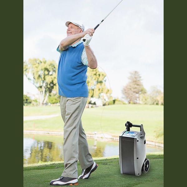 Man playing golf on a course with a oxygen concentrator in the foreground
