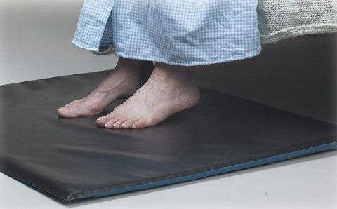 Person wearing checkered pajama pants standing on a black mat.