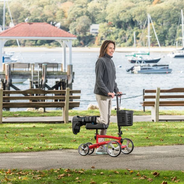 Woman using a knee walker in a park by a waterfront