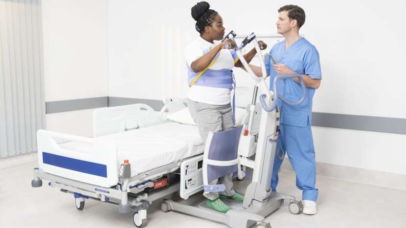 Two healthcare professionals with a patient transfer cart in a hospital setting.