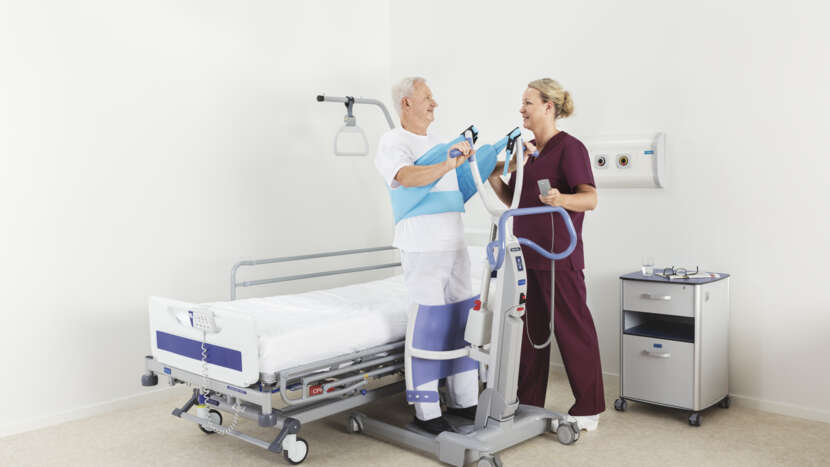 Two healthcare professionals assisting a patient in a hospital room.