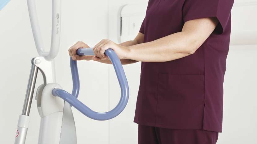 Person in maroon scrubs using a white and blue exercise device.