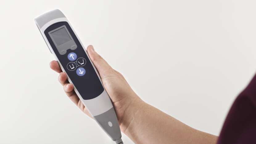 Hand holding a digital device with a screen and buttons on a white background