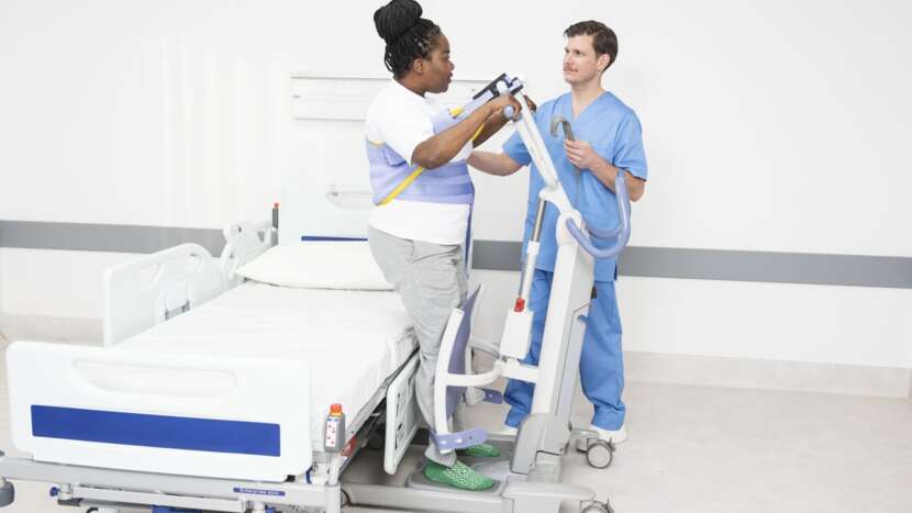 Two healthcare professionals with a patient lift in a hospital setting