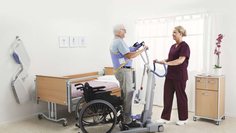 Physiotherapist assisting a patient using a treadmill in a hospital room.