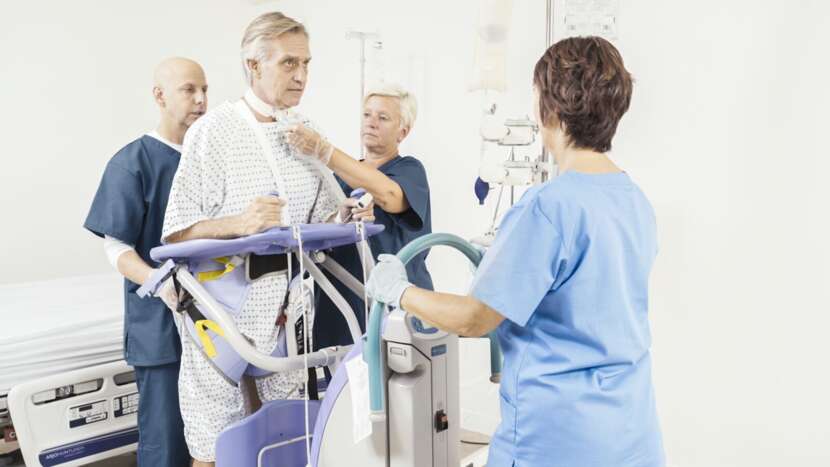 nurses helping a client stand using a lift