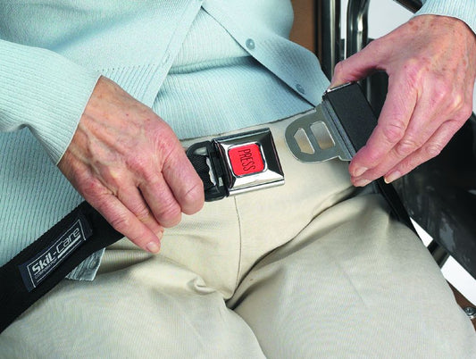 Person in a wheelchair being helped to fasten a safety belt with a visible brand logo.