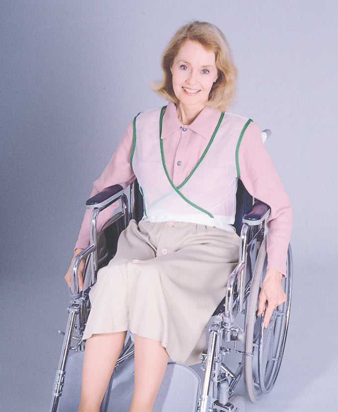 Woman in a wheelchair wearing a pink blouse with green trim against a gray background