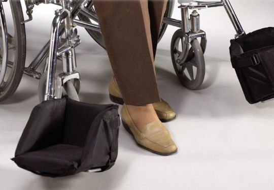 Person using a black footrest with a wheelchair on a white background