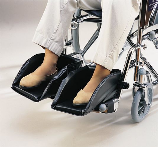 Wheelchair with footrests being used by a person wearing white pants and beige shoes.