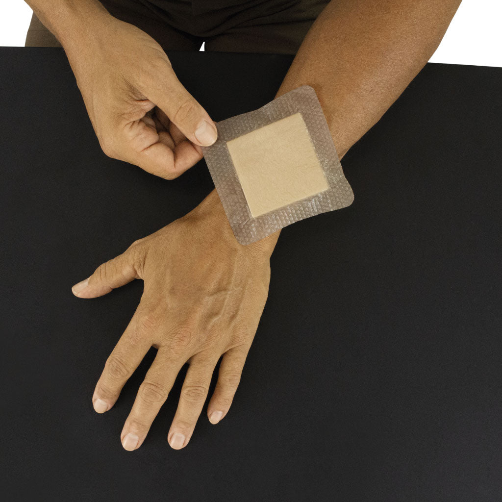 Person applying a bandage to their wrist on a black background