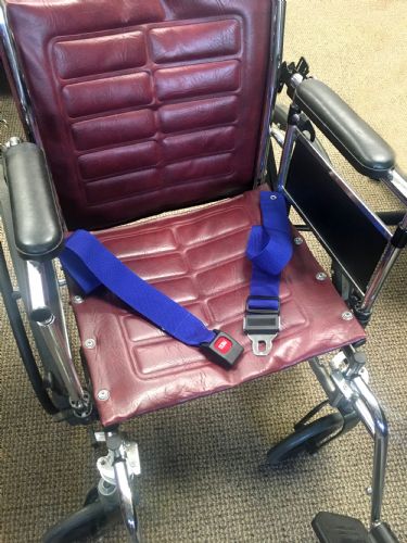 Wheelchair with a blue safety harness on a carpeted floor