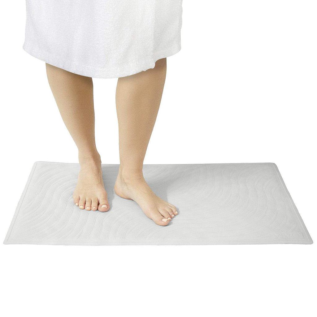 Person standing on a white bath mat with a white towel draped over their shoulders.
