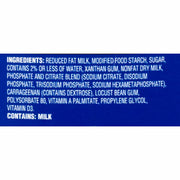 A close-up of a blue label section showing white text with ingredients listed, including reduced fat milk, modified food starch, sugar, xanthan gum, nonfat dry milk, phosphate and citrate blend, carrageenan, locust bean gum, polysorbate 80, vitamin A palmitate, propylene glycol, and vitamin D3. Below the ingredients, it states 'CONTAINS: MILK'.