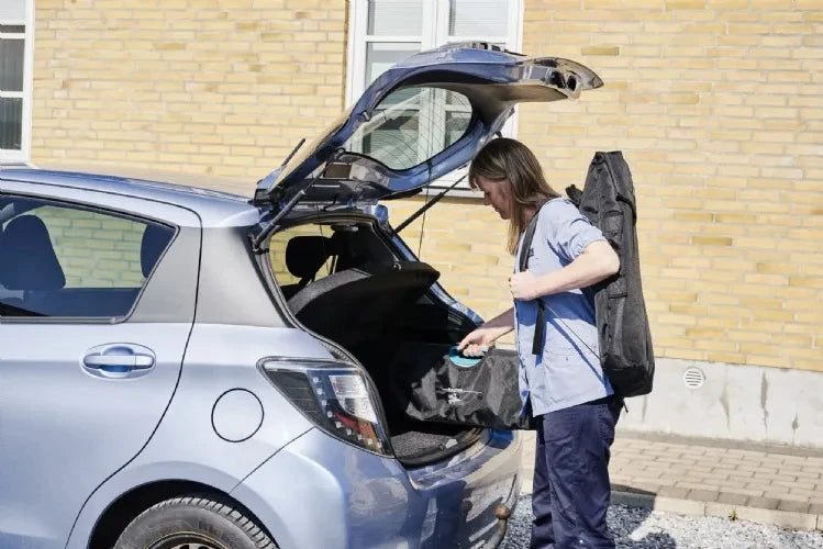 woman carrying chair on back about to put into car