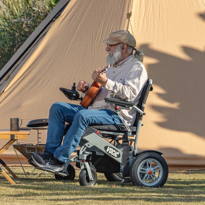 Man in a wheelchair playing a flute outdoors near a tent